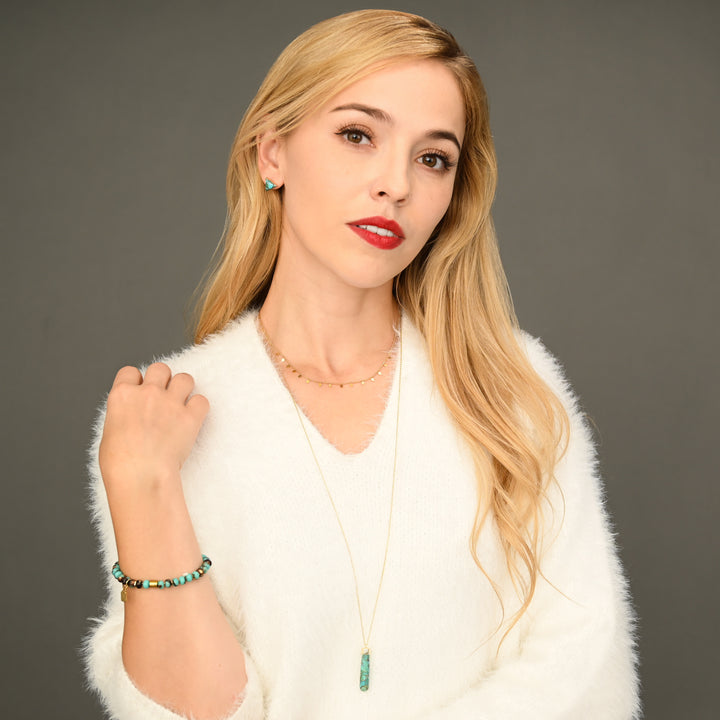 A woman wearing turquoise and gold jewellery pieces, fair trade jewellery company, unique xmas gifts